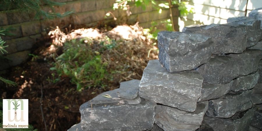 compost hidden in backyard behind decorative wall