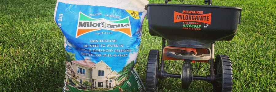 Bag of Milorganite and spreader in the lawn