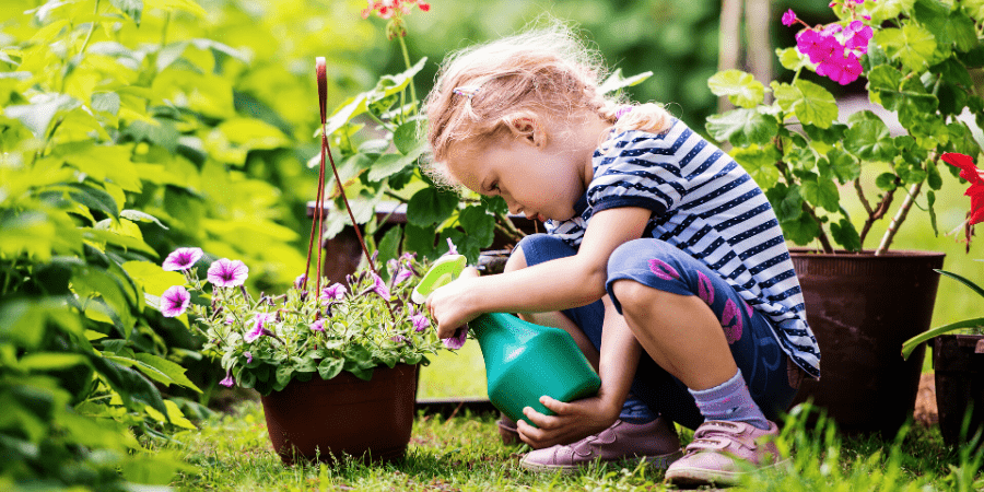 Outdoor Activites Kid in Garden watering a plant